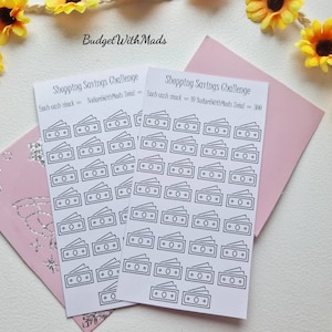 May include: Two sheets of white paper with black outlines of stacks of money. The text "Shopping Savings Challenge" is at the top of each sheet. The text "Each cash stack = 10 BudgetWithMads Total = 300" is at the bottom of the right sheet.
