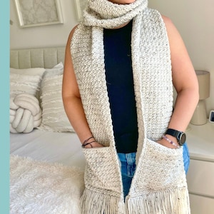 May include: A long, cream-colored crochet scarf featuring a speckled texture, two large front pockets, and fringe trim at the bottom edges. The word PATTERN is printed vertically in black capital letters on the left side of the image.
