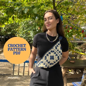Może przedstawiać: Wzór na szydełku PDF na niebiesko-białą torebkę na ramię z kwadratów babci. Torebkę nosi osoba w czarnej koszulce i czarnych spodniach. Zdjęcie zostało zrobione na zewnątrz przed żółtym ogrodzeniem.