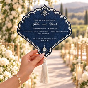 May include: A fan-shaped wedding program in deep navy blue with a white damask pattern and gold border. It features the text John and Sarah, September 18 2027, Napa Valley, and event times. A cream-colored tassel hangs from the bottom of the card.