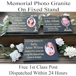 May include: Three black granite memorial photo plaques with gold lettering and a photo of the deceased. The plaques are on a wooden surface with white flowers. The text on the plaques reads "In Loving Memory Of" followed by the name of the deceased and their dates of birth and death. The text also includes a description of the deceased, such as "Loving Wife, Mum and Sister".
