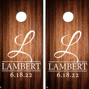 May include: Two wooden cornhole boards with a white cursive "L" and the text "LAMBERT 6.18.22" on each board.