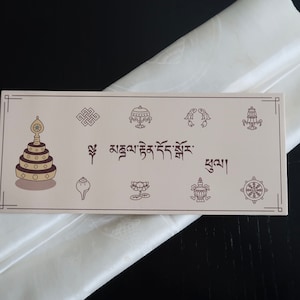May include: A white silk scarf with a beige card featuring a Tibetan prayer wheel, a conch shell, a lotus flower, a turtle, a Dharma wheel, and the text "བཀྲ་ཤིས་བདེ་ལེགས་" in Tibetan script.