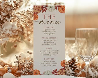Könnte beinhalten: Eine vertikale Menükarte mit dem Schriftzug "THE menu" in eleganter Schrift. Die Speisekarte bietet herbstliche Gerichte wie Kürbissuppe und Kürbiskuchen. Dekorative Kürbisse und Blätter schmücken die oberen und unteren Ränder der Karte. Ein Weinglas befindet sich im Vordergrund.