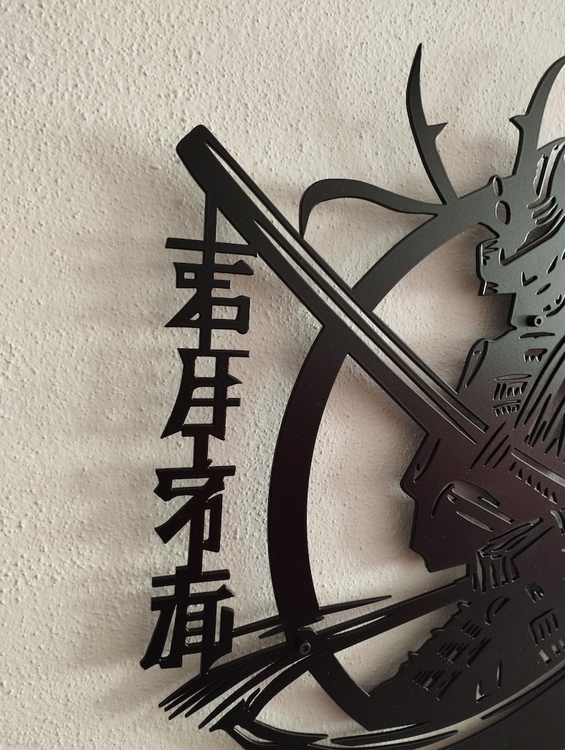 K&ouml;nnte beinhalten: Schwarze Metall-Wandkunst mit einem Samurai-Krieger mit Katana und japanischen Schriftzeichen. Das Kunstwerk ist aus Metall geschnitten und an einer wei&szlig;en Wand befestigt. Der Helm und die R&uuml;stung des Samurai sind detailliert.