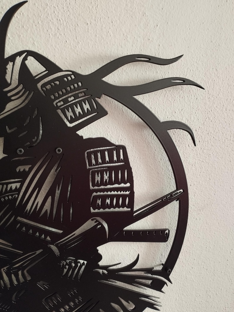 K&ouml;nnte beinhalten: Schwarze Metall-Wandkunst, die einen Samurai-Krieger im Profil zeigt. Das Kunstwerk zeigt detaillierte Darstellungen des Helms, der R&uuml;stung und eines Katana. Das Design umfasst einen kreisf&ouml;rmigen Rahmen und dekorative Elemente.