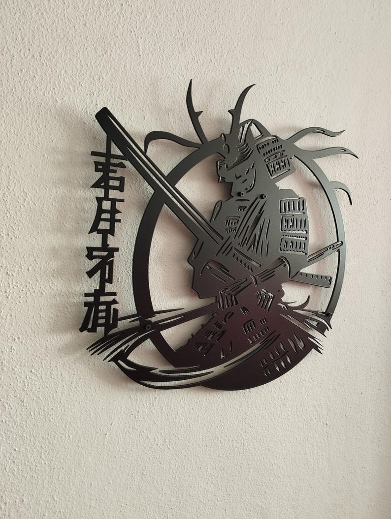 K&ouml;nnte beinhalten: Schwarze Metall-Wandkunst, die einen Samurai-Krieger in voller R&uuml;stung mit einem Katana darstellt. Das Kunstwerk ist in einem kreisf&ouml;rmigen Rahmen mit stilisierten Elementen und japanischen Schriftzeichen auf der linken Seite angeordnet. Auf einer strukturierten wei&szlig;en Wand montiert.