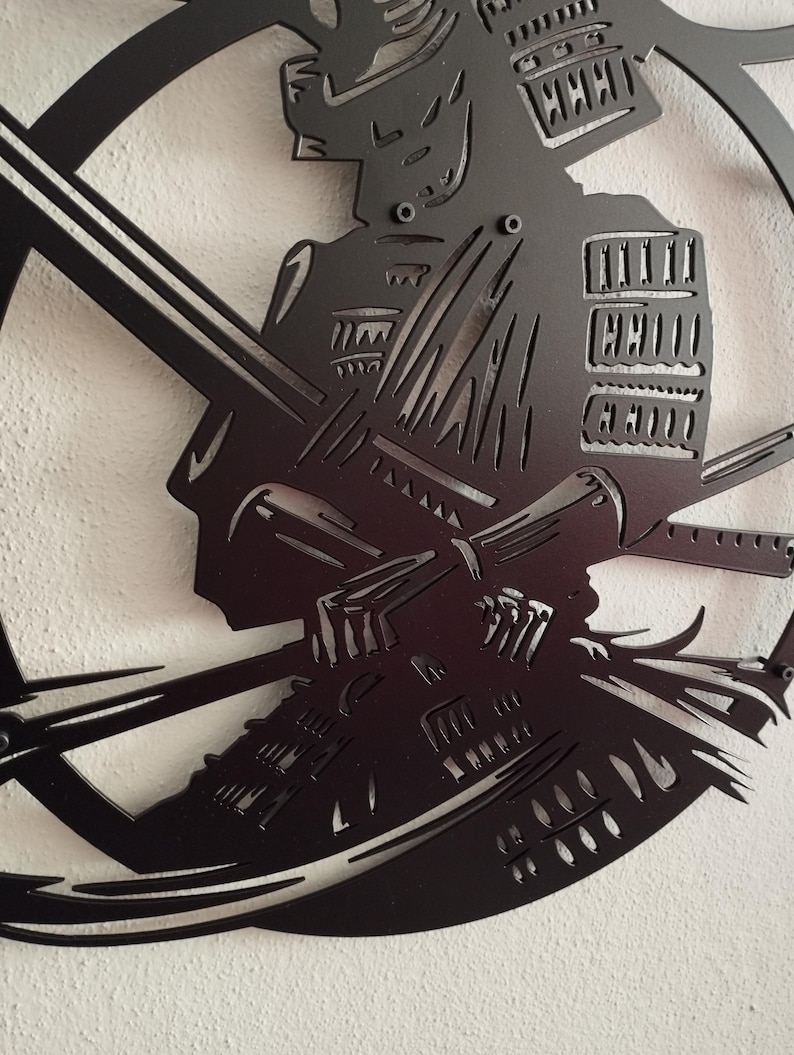 K&ouml;nnte beinhalten: Schwarze Metall-Wandkunst, die einen Samurai-Krieger im Profil zeigt, der ein Katana h&auml;lt. Das Kunstwerk ist aus einem einzigen Metallblech geschnitten und zeigt detaillierte Darstellungen der R&uuml;stung und des Helms. Der Samurai befindet sich in einem kreisf&ouml;rmigen Rahmen.