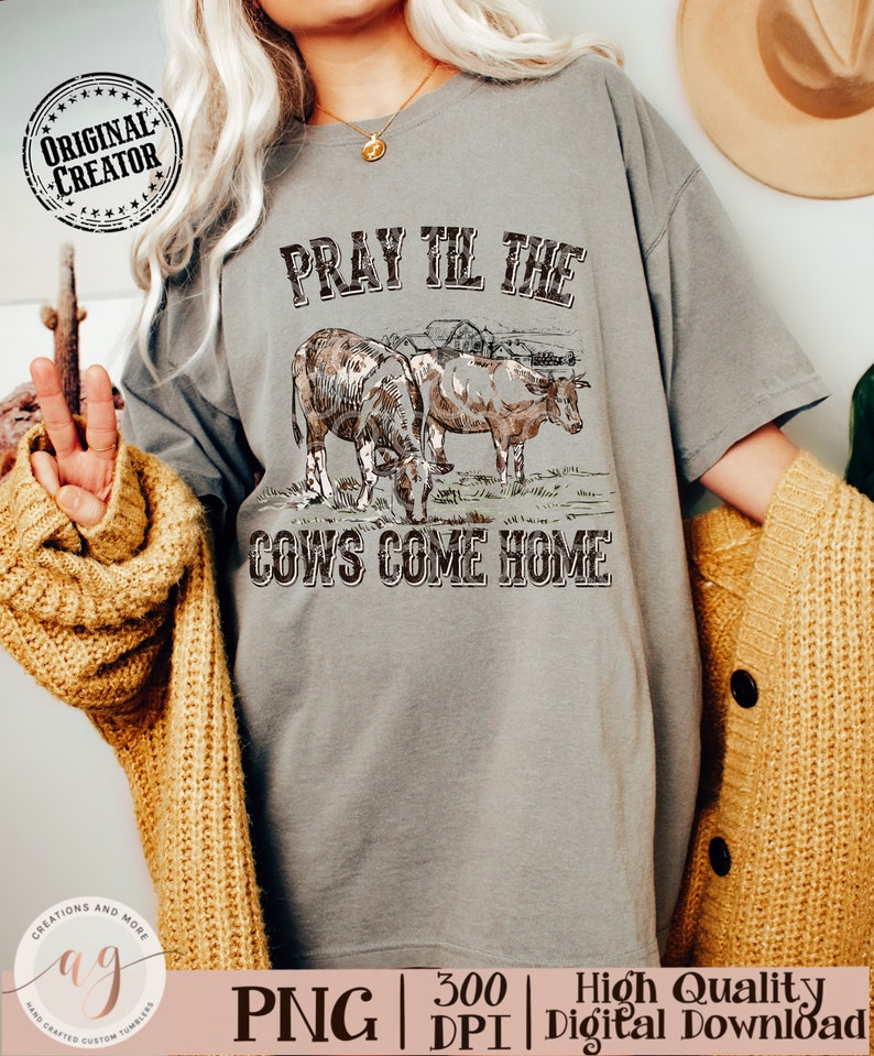 May include: A gray t-shirt with the text "Pray Till The Cows Come Home" in black. The design features a vintage illustration of two cows in a field.