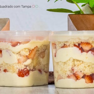 May include: Two clear plastic containers filled with a layered dessert. The dessert is made with white cake, whipped cream, and fresh strawberries. The containers are labeled "Pote Quadrado com Tampa".