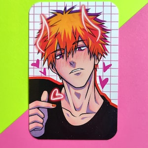May include: A rectangular sticker featuring an anime-style character with orange hair and glowing white horns. The character is blushing, with pink hearts and a hand gesture forming a heart. The background is a grid pattern.