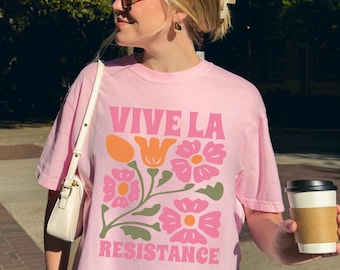 May include: Pink t-shirt with a floral design and the text "Vive La Resistance".