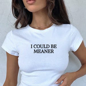 May include: White cropped t-shirt with short sleeves and the text "I could be meaner" printed in black.