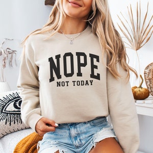 May include: A beige sweatshirt with black text that reads "NOPE NOT TODAY".
