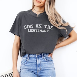 May include: A charcoal grey t-shirt with the text "DIBS ON THE LIEUTENANT" printed in white.
