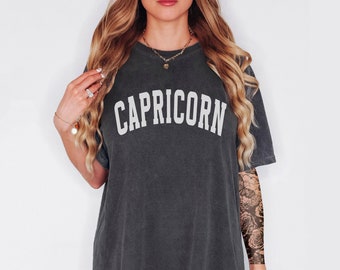 Könnte beinhalten: Ein überdimensioniertes T-Shirt in Dunkelgrau mit dem Wort "STEINBOCK" in Weiß auf der Vorderseite.