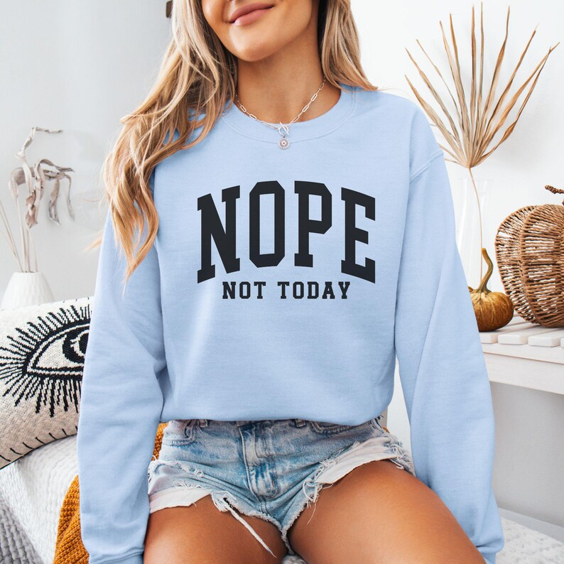 May include: A light blue sweatshirt with the text "NOPE NOT TODAY" in black lettering.