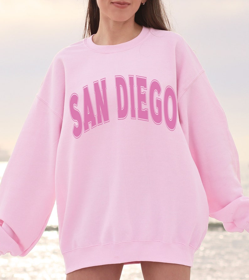 May include: Pink sweatshirt with the text "SAN DIEGO" in a pink outlined font.