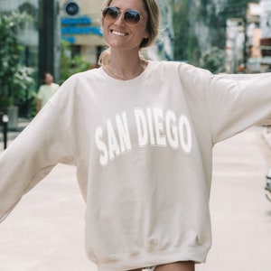May include: A cream colored sweatshirt with the text "SAN DIEGO" in white outlined letters.