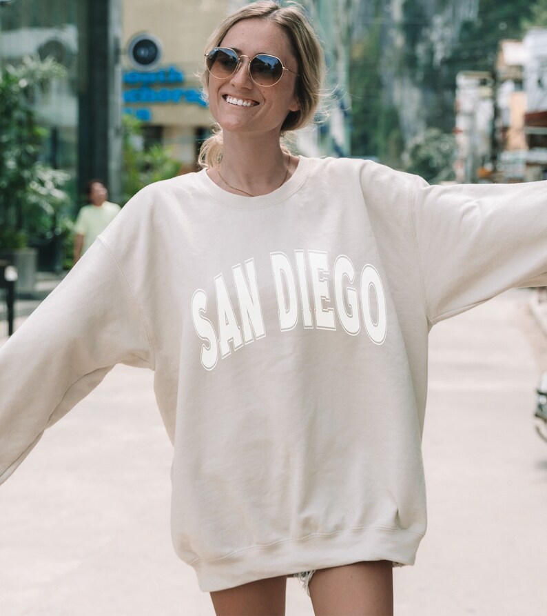 May include: A cream colored sweatshirt with the text "SAN DIEGO" in white outlined letters.