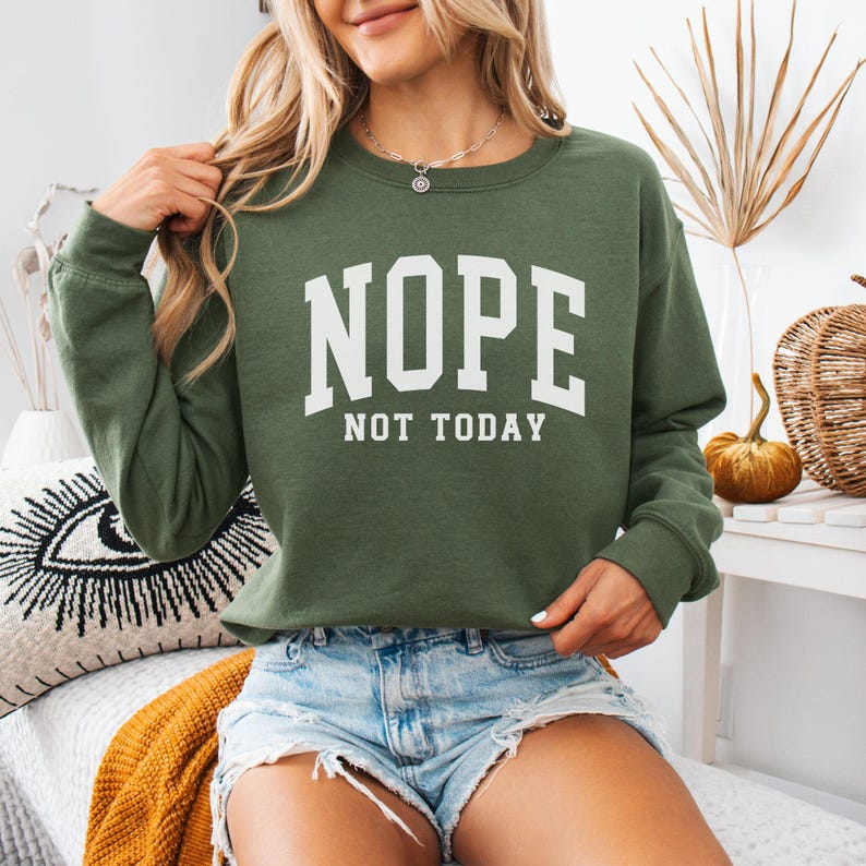 May include: A green sweatshirt with the text "NOPE NOT TODAY" in white letters. The sweatshirt is a relaxed fit and has a crew neck.