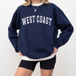 Puede incluir: Una sudadera azul marino con el texto "WEST COAST" impreso en blanco en la parte delantera.