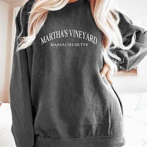 May include: A dark grey sweatshirt with the text "Martha's Vineyard Massachusetts" printed on the front.