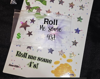 Puede incluir: Una hoja de desafío para rascar blanca con el texto "Roll Me some 4's!" y "Save $118+". La hoja está decorada con gráficos de estrellas y dinero. Incluye un sobre transparente. El texto en la parte inferior dice "Come with your Choice of A6 or A5 Envelope to store your cash!"