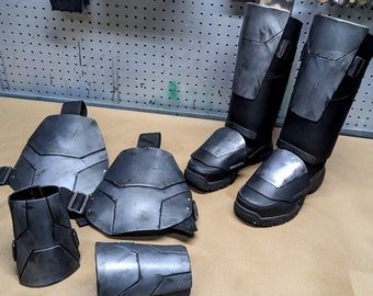 May include: A set of black and gray armor pieces for cosplay or costume. The set includes knee pads, shin guards, and forearm guards. The armor is made of a durable material and has a realistic look.