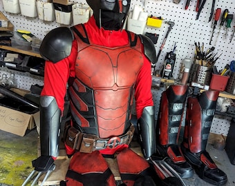 Può includere: Un costume rosso e nero con un elmetto, un'armatura per il petto, protezioni per le braccia, protezioni per le gambe e artigli. Il costume è fatto di schiuma ed è progettato per assomigliare a un supereroe.