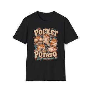 Puede incluir: Una camiseta negra de manga corta con un gráfico de cinco hámsteres en varias posturas. El texto dice POCKET POTATO y TINY BODY SERIOUS SNACK CAPACITY. El diseño incluye pequeñas semillas de girasol y estrellas en tonos naranja, azul y crema.