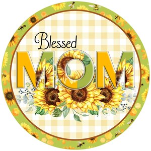 Könnte beinhalten: Ein rundes, grün-gelbes Schild mit kariertem Hintergrund und den Worten "Blessed Mom" in gelben Buchstaben, umgeben von Sonnenblumen und Bienen.