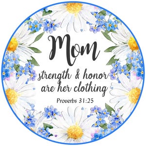 Puede incluir: Un círculo blanco con un borde azul que presenta un diseño floral de margaritas blancas y nomeolvides azules. El texto "Mom strength & honor are her clothing Proverbs 31:25" está escrito en negro.