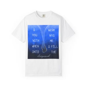 May include: White t-shirt with a blue and black graphic. The graphic features the text "I wish you were with me when I fell into the deep end". The shirt has a crew neck and short sleeves.