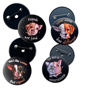 Könnte beinhalten: Eine Sammlung schwarzer runder Ansteckbuttons mit Tierillustrationen. Jeder Button zeigt ein geteiltes Bild von zwei Tieren, wie einem Hund und einem Schwein, mit Texten wie "Friends not food" und "Same same but different."