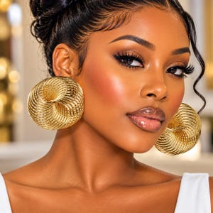 May include: A pair of large, circular gold-toned earrings featuring a complex, multi-layered spiral wire design. The earrings are constructed from thin, concentric metallic coils that create a hollow, spherical, and dimensional appearance.