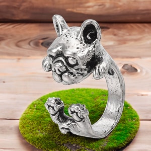 May include: Silver ring featuring a detailed, three-dimensional French bulldog design. The ring is adjustable and open-ended.