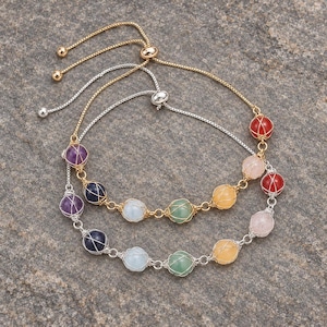 May include: Two adjustable bracelets featuring spherical beads encased in thin wire cages. One bracelet has a gold-tone chain, while the other has a silver-tone chain. The beads display a variety of colors including purple, blue, light blue, green, yellow, pink, and red.