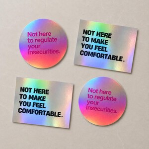 Könnte beinhalten: Vier holografische Aufkleber mit zwei verschiedenen Designs. Zwei runde Aufkleber zeigen den magentafarbenen Text Not here to regulate your insecurities. Zwei rechteckige Aufkleber zeigen den schwarzen Text NOT HERE TO MAKE YOU FEEL COMFORTABLE.