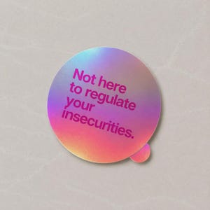 May include: A circular sticker with a holographic, iridescent finish that shifts between shades of pink, purple, and gold. The text "Not here to regulate your insecurities." is printed in a bold, dark magenta font across the center of the sticker.