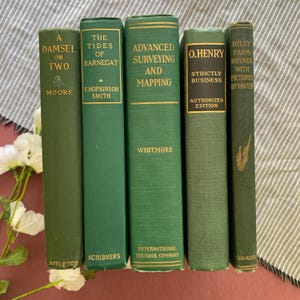 Puede incluir: Una colección de cinco libros antiguos de tapa dura en varios tonos de verde. Los títulos incluyen "A Damsel or Two", "The Tides of Barnegat", "Advanced Surveying and Mapping", "Strictly Business" y "Riley Farm-Rhymes with Pictures".