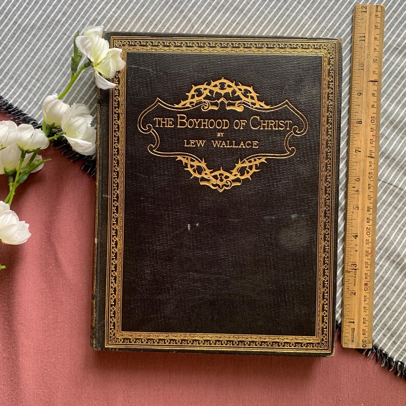 Peut inclure: Un livre reli&eacute; en cuir noir avec des lettres dor&eacute;es et une bordure d&eacute;corative. Le titre est "The Boyhood of Christ" par Lew Wallace.