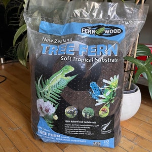 May include: A bag of New Zealand Tree Fern Soft Tropical Substrate for terrariums. The bag features a green fern leaf logo and the text "Fern Wood". The bag also features images of reptiles, frogs, and plants.