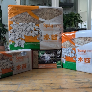 Puede incluir: Cuatro paquetes de musgo sphagnum, también conocido como musgo de agua, para el cultivo de plantas. Los paquetes están etiquetados con "Spagmoss" y "水苔" en japonés. Los paquetes son de diferentes tamaños, siendo el más grande de 40 litros.