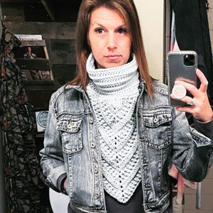 May include: A woman wearing a light blue crocheted cowl neck scarf with a denim jacket.