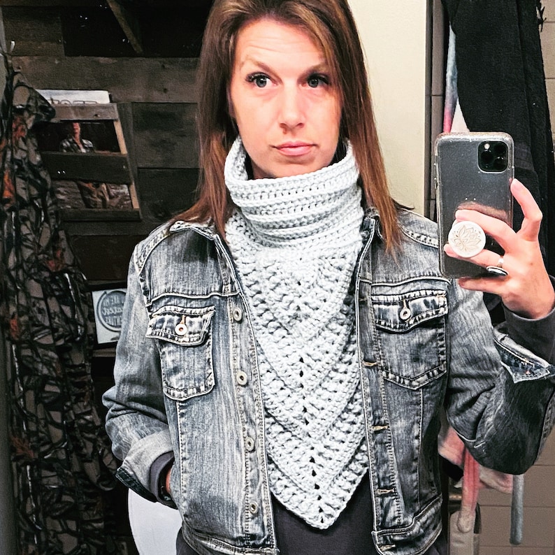 May include: A woman wearing a light blue crocheted cowl neck scarf with a denim jacket.