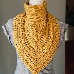 May include: A mustard yellow crocheted cowl neck scarf with a triangular shape.