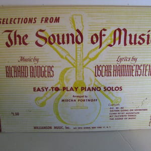 May include: Sheet music cover for "The Sound of Music" piano solos. The cover features a yellow background with a guitar and musical instrument graphic. Text includes the title, composer names Richard Rodgers and Oscar Hammerstein, and song titles.