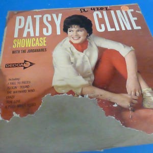 May include: A vintage vinyl record album cover featuring Patsy Cline, a country music singer, with the title "Showcase" and the text "With the Jordanaires" and "Decca" on the cover. The album cover is red, white, and black.