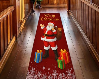 Op de afbeelding: Een rode kerstlopermat met de kerstman, een zak met speelgoed en cadeaus. De loper heeft de woorden "Merry Christmas" in gouden letters en sneeuwvlokken.